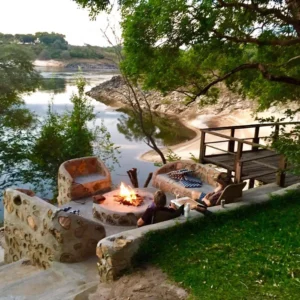 A stone fire pit and wooden viewing deck on the bank of the Zambezi at Ngonye River Camp, near Sioma