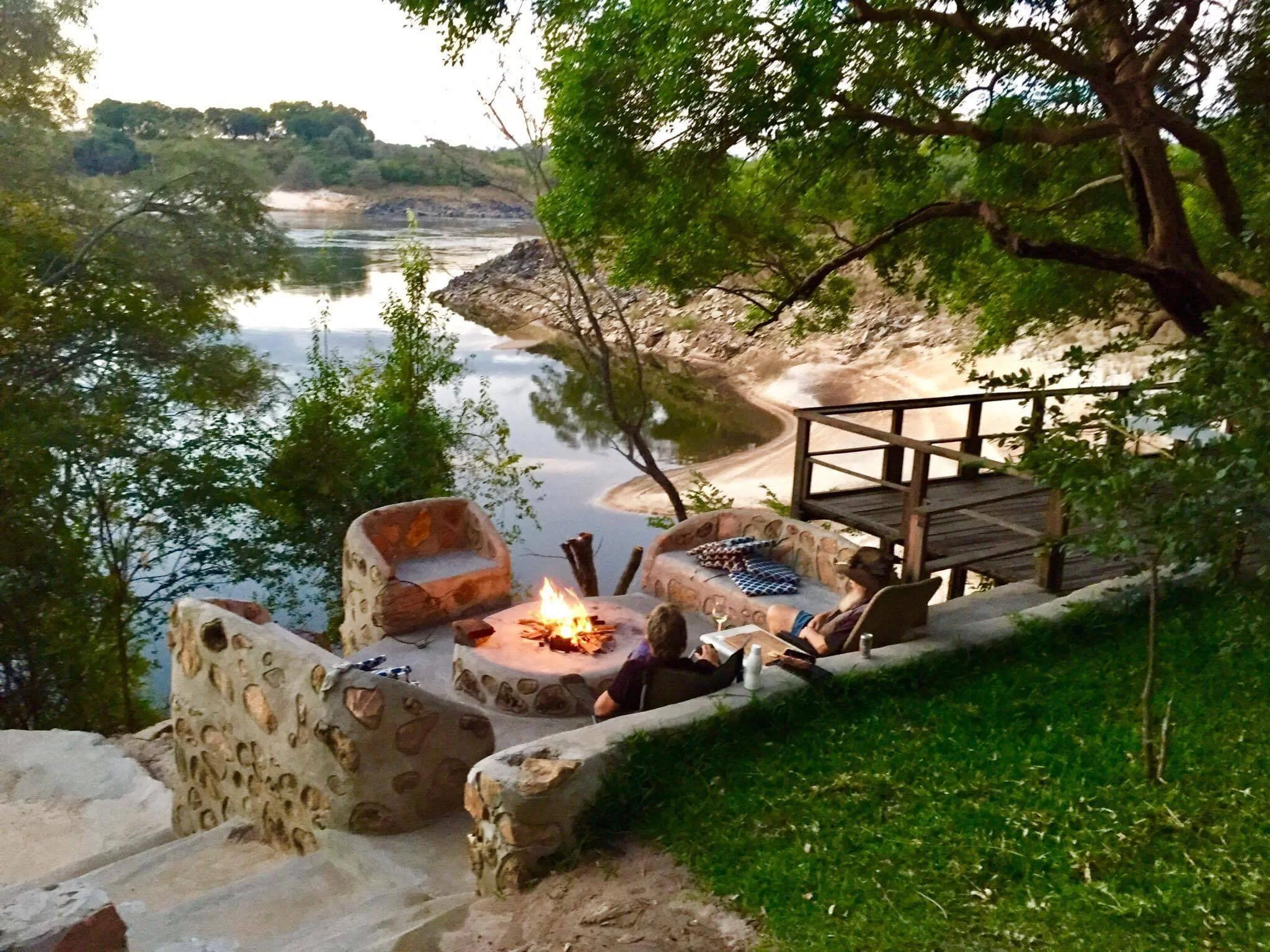 A stone fire pit and wooden viewing deck on the bank of the Zambezi at Ngonye River Camp, near Sioma