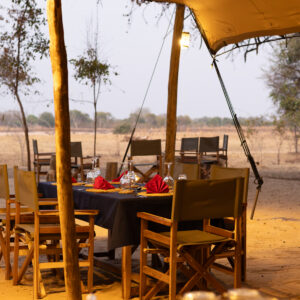 A tenda-refeitório de lona aberta dos lados e a mesa posta no Kutandala Camp, Parque Nacional de North Luangwa