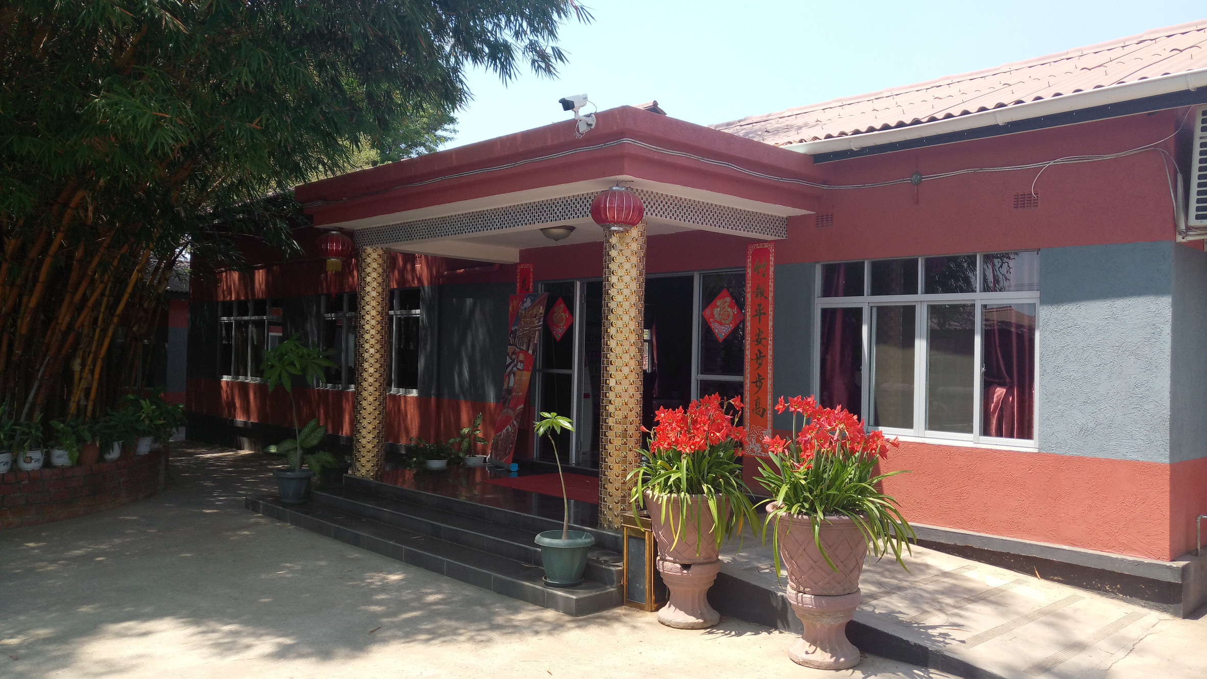 The red-painted entrance frontage of the Red Lantern Hotel in Lusaka, with gold pillars and hanging lanterns