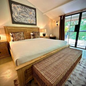 Una camera del Sakae Paradise Resort a Lusaka, con letto dalla struttura in legno e una finestra a tutta altezza affacciata sugli alberi