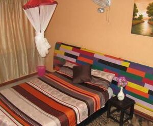 A private room at Flintstones Backpackers in Lusaka, with a striped patchwork headboard, woven blanket and mosquito net