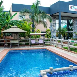 The swimming pool, thatched gazebo and garden in front of the main block at Crossroads Hotel, Ndola