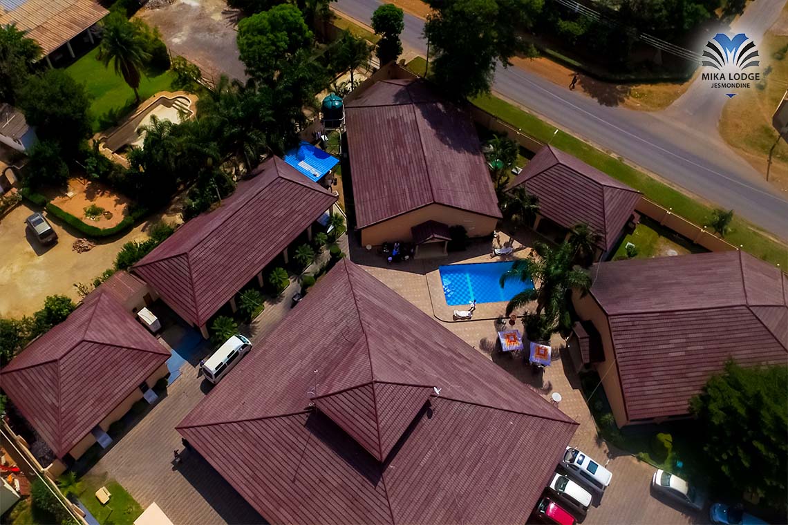 Aerial view of the red-tiled chalet roofs and swimming pool at Mika Lodge, Jesmondine, Lusaka