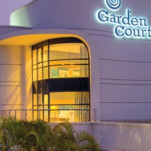 The floodlit curved entrance facade of Garden Court Kitwe at dusk