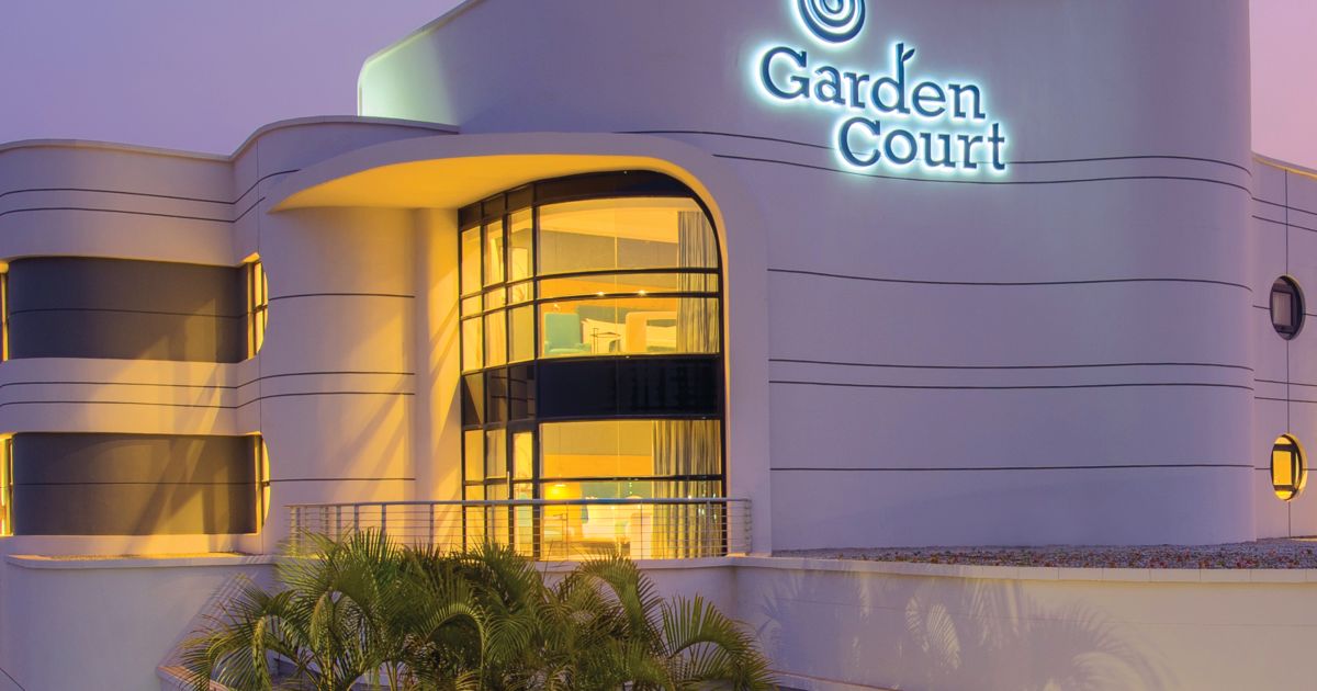 The floodlit curved entrance facade of Garden Court Kitwe at dusk