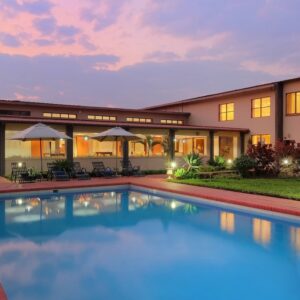 The outdoor pool at dusk in front of the lit guest-room wing at Protea Hotel by Marriott Chipata