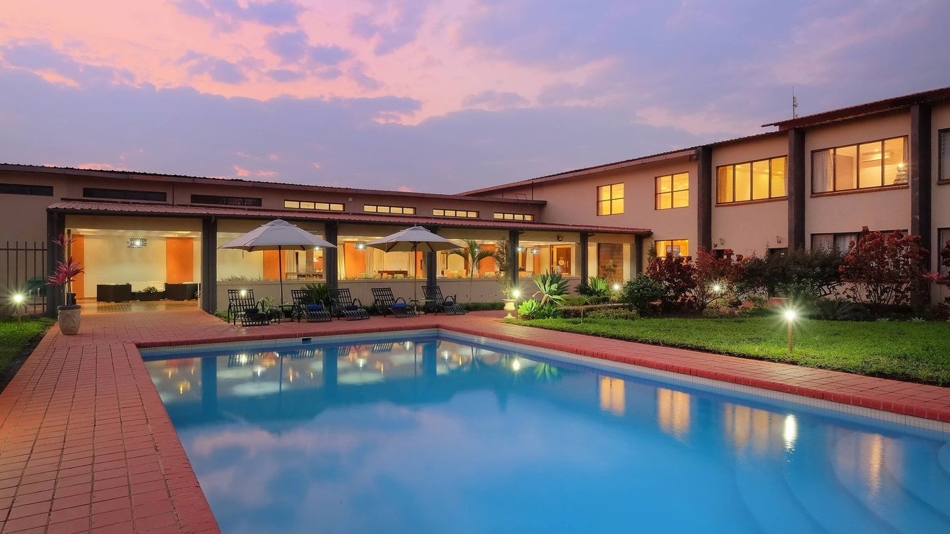 The outdoor pool at dusk in front of the lit guest-room wing at Protea Hotel by Marriott Chipata