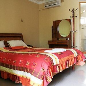 Ein Gästezimmer der Villa Executive Lodge in Lusaka mit Doppelbett im Holzrahmen, Frisiertisch und Durchgang zum eigenen Bad