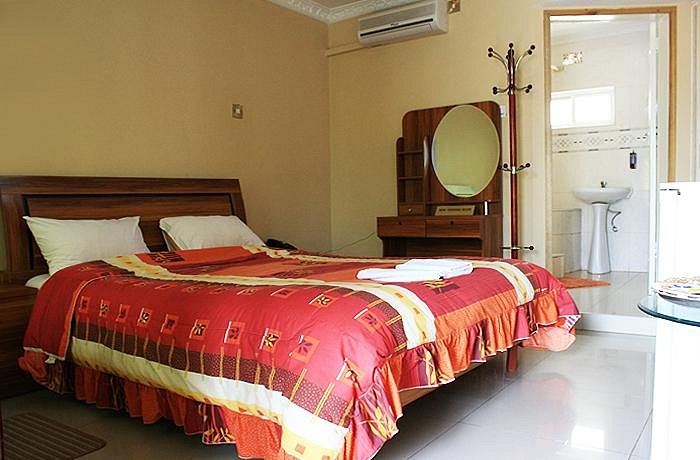 Una camera del Villa Executive Lodge a Lusaka, con letto matrimoniale dalla struttura in legno, toeletta e porta del bagno privato