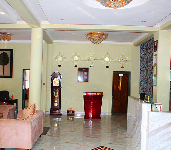 The marble-floored reception lobby of the Sherbourne Hotel in Kitwe, with a red front desk below a row of world clocks