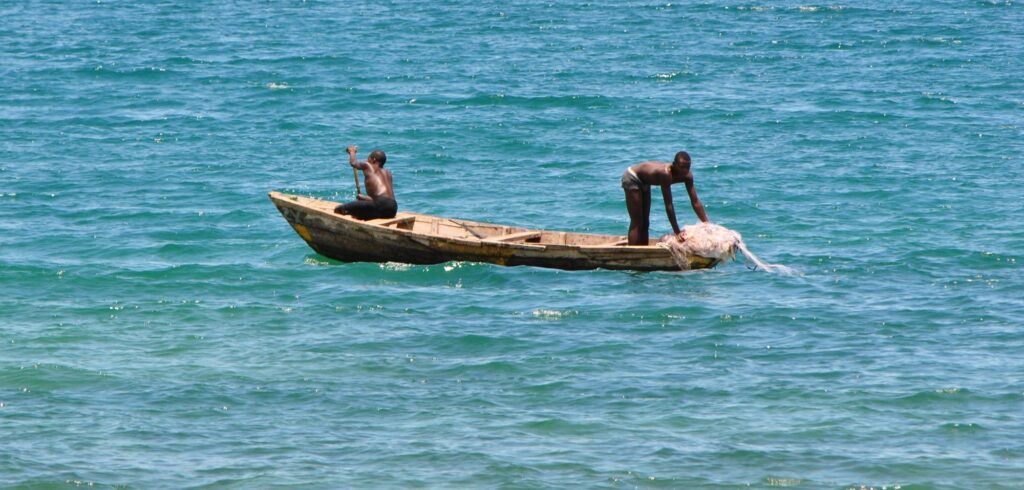 Fishermen in a dugout canoe on the turquoise water of Lake Tanganyika in northern Zambia