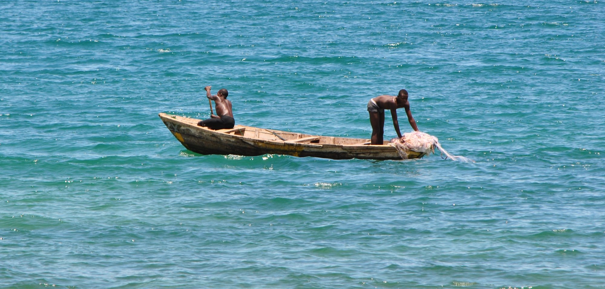 Fishermen in a dugout canoe on the turquoise water of Lake Tanganyika in northern Zambia